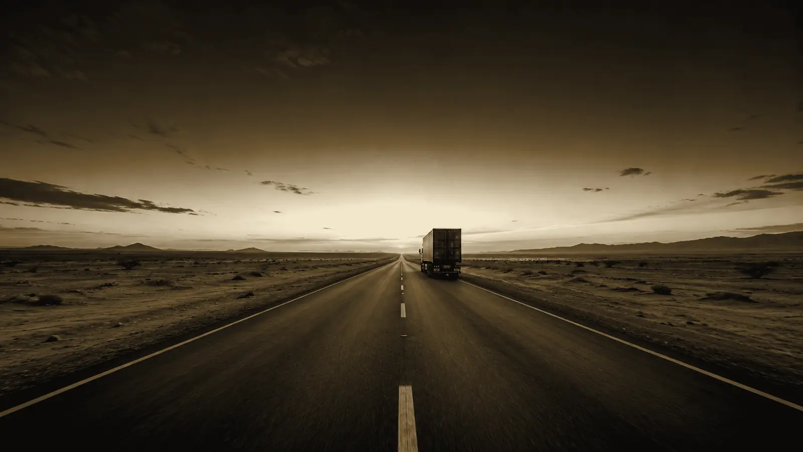 A container truck on a straight desert road at dusk